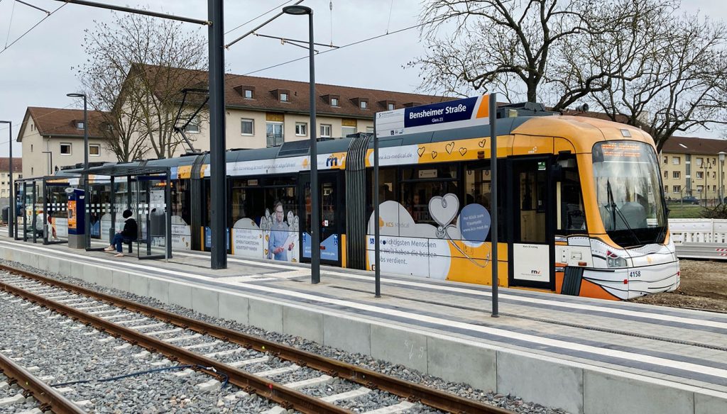 Eine Straßenbahnhaltestelle an der eine Straßenbahn hält.