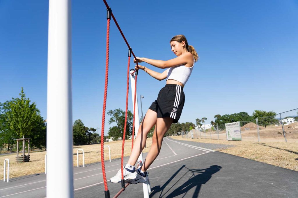 Eine junge Frau trainiert an Seilen auf einer Station der Calisthenics Anlage auf dem Loop in Franklin.