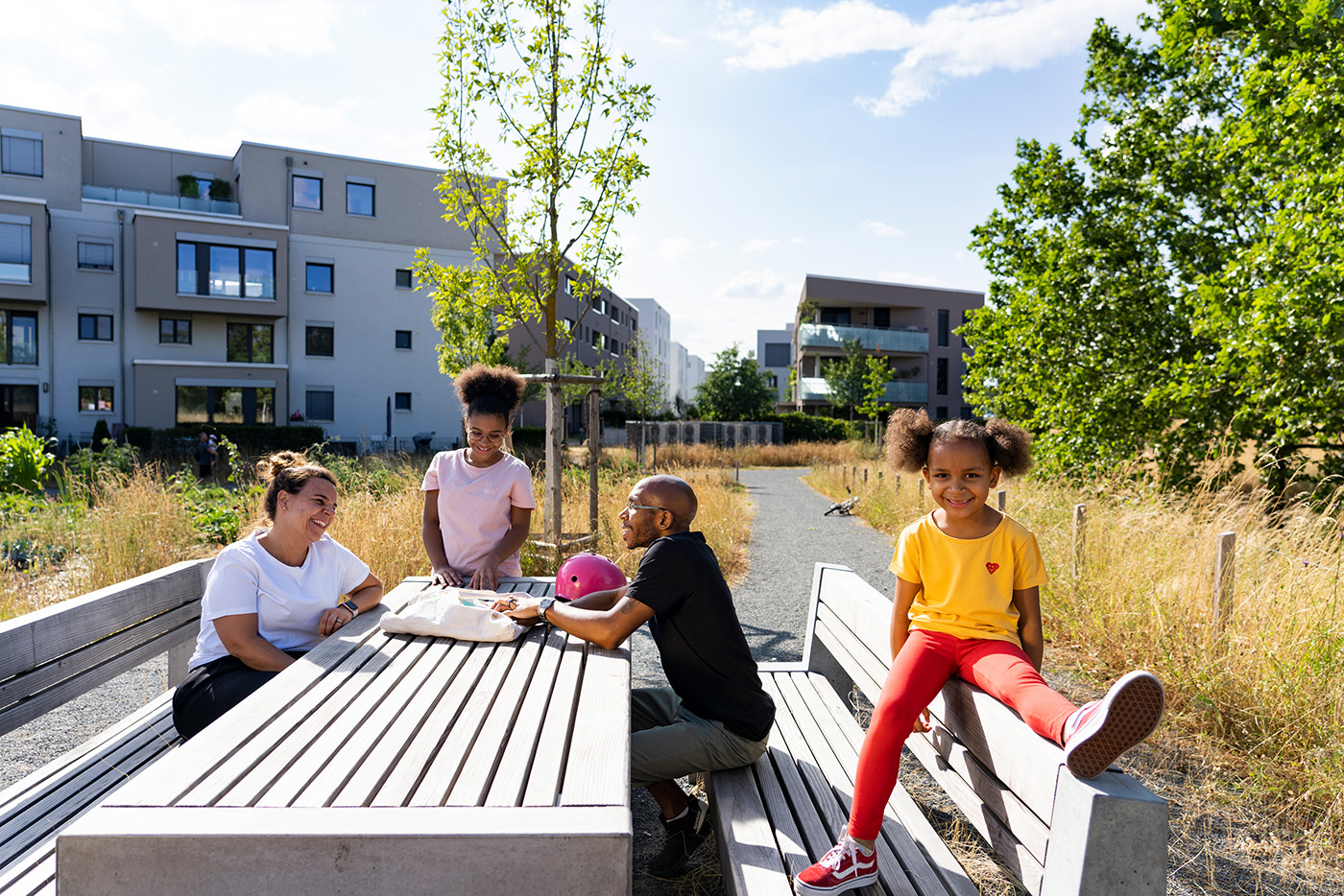 Eine Familie mit zwei Kindern sitzen an einem Tisch im Freien.