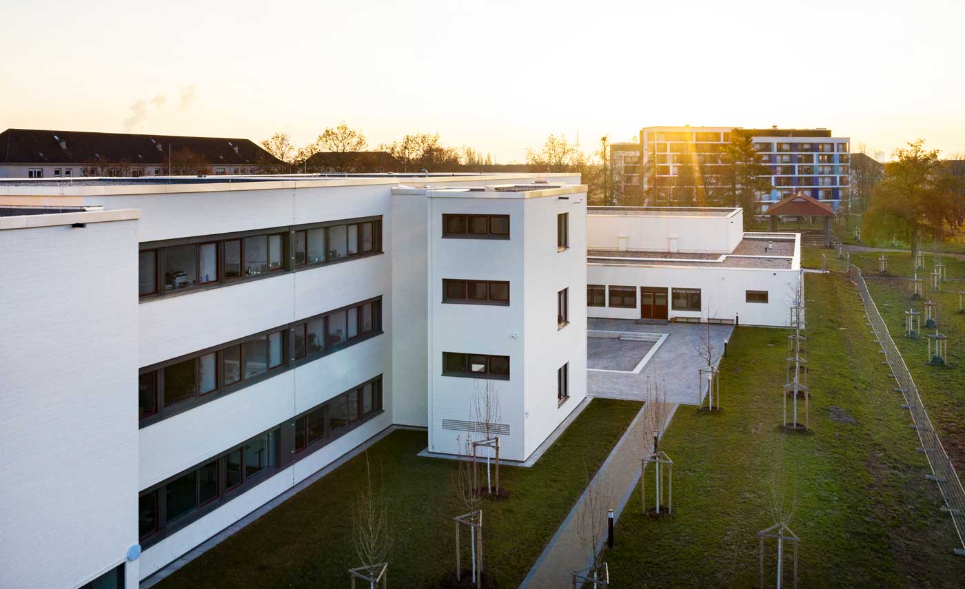 Ein weißes Gebäude mit Sonnenuntergang im Hintergrund.