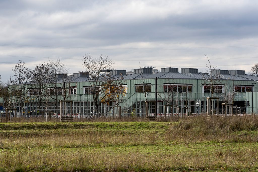 Außenansicht des Neubaus der Franklinschule mit Wiese und herbstlichen Bäume im Vordergrund