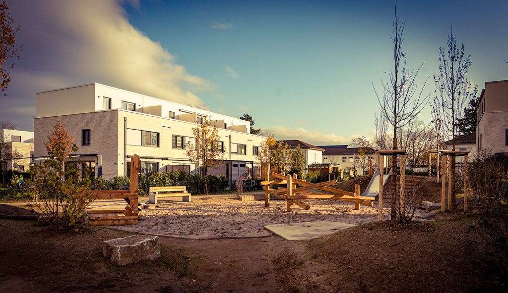 Spielplatz in der südlichen Offizierssiedlung für Kleinkinder mit Holzkletterstruktur, Sandkiste mit Spielangebot und breiter Rutsche