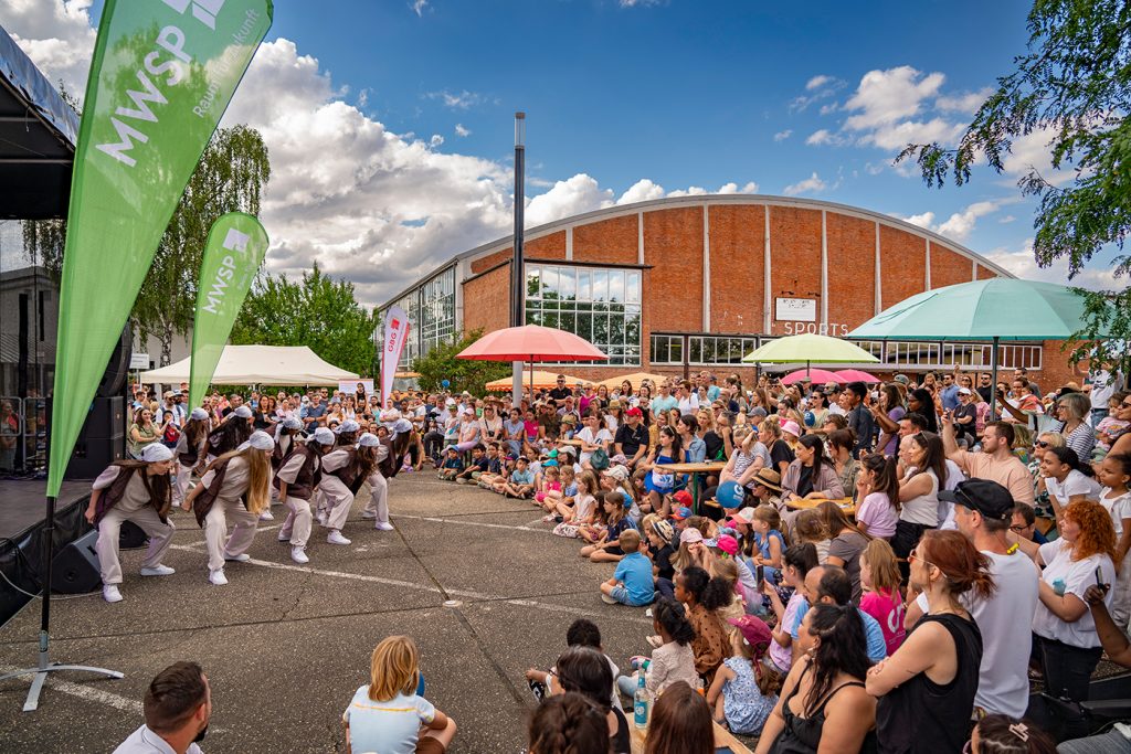 Tanzdarbietung einer Jugendgruppe vor der Bühne beim FRANKLIN Fest mit großem Publikum. Im Hintergrund ist die ehemalige Sporthalle der Amerikaner (Sports Arena) zu sehen.