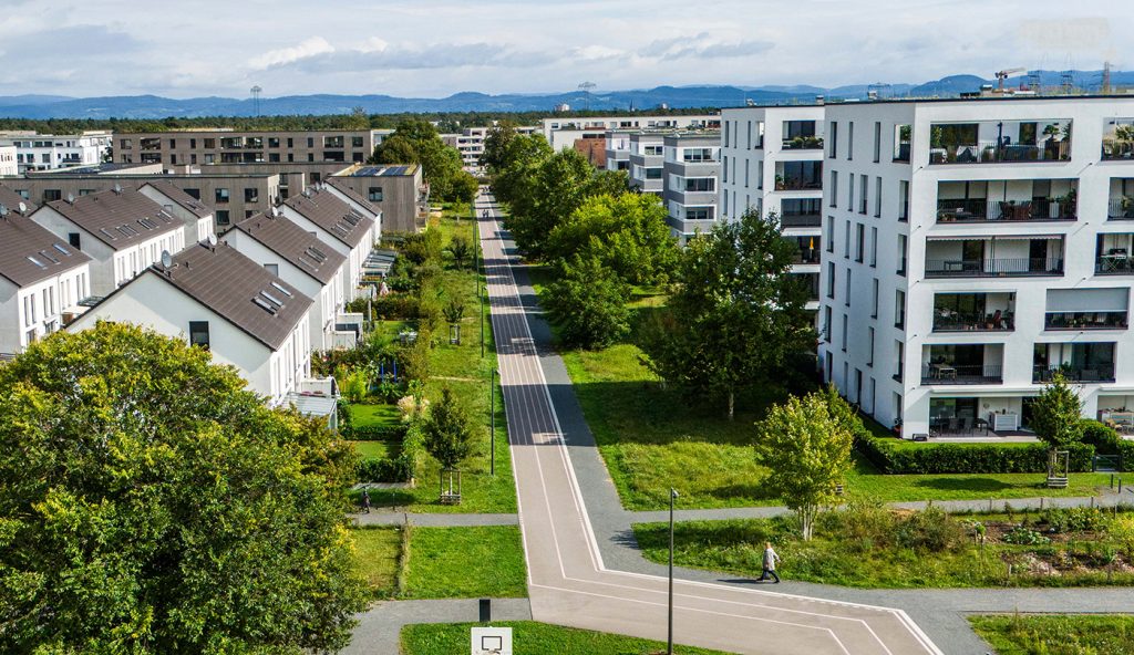 Drohnenaufnahme eines langen Fahrrad- und Fußgängerwegs mit Grünflächen und Bäumen an den Seiten