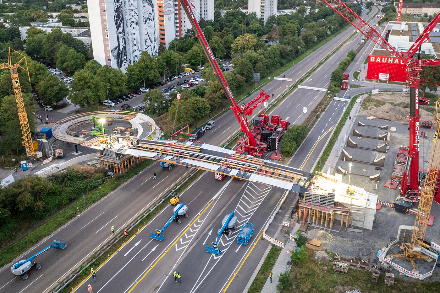 Drohnenaufnahme mit Blick auf die gesperrte Bundesstraße 38 und die Baustelle Franklin Steg. In der Mitte setzt ein großer Kran gerade die Brücke ein. Links im Hintergrund sind 4 Hochhäuser des Stadtteils Vogelstand sichtbar.