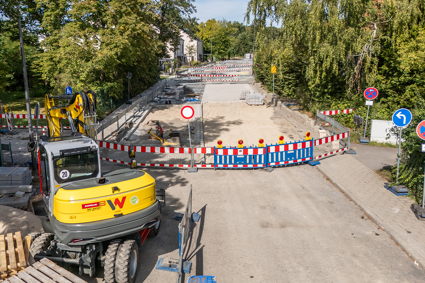 Blick auf die Straßenbaustelle Wasserwerkstraße-Nord mit Absperrbarken. Links im Vordergrund ist ein Bagger zu sehen.
